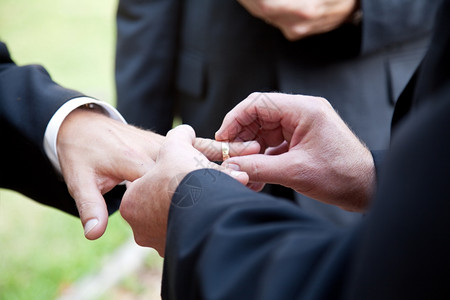 一名新郎在同志婚礼上将戒指戴在另一个男人的手指上图片