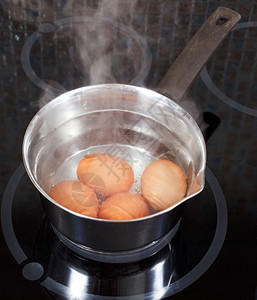 厨房电炉的金属锅中煮鸡蛋图片
