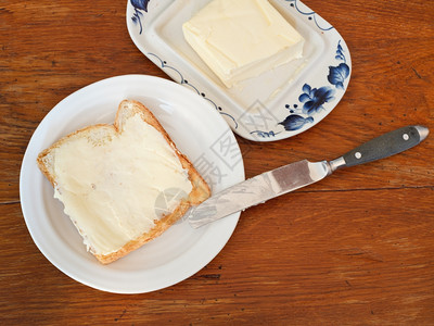 黄刀镇白板上的面包和黄油三明治刀奶油木板上的黄背景