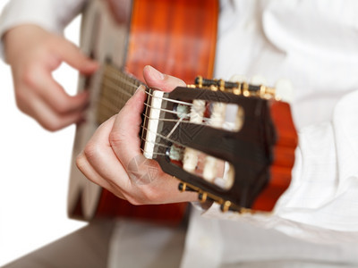 男人在古典音乐吉他上演奏关闭与世隔绝的白色背景图片