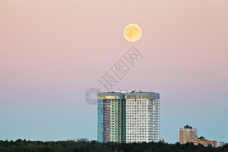 夏夜在城市住宅上空粉红天中满月图片