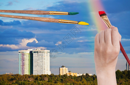 彩虹与手素材自然概念与油漆刷画手城市房屋上蓝色云彩虹背景