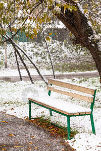 秋天在城市公园第一次下雪和空板凳图片