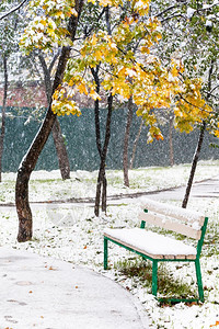 秋天第一次降雪下城市公园的空凳子图片