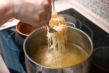 烹饪汤从陶瓷锅中将煮的酸菜调饭到配肉汤的酱锅图片