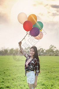 一个快乐的漂亮女人肖像在绿地有气球快乐的漂亮女人气球图片