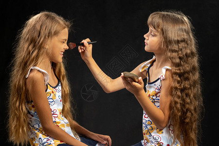 女孩用刷鼻孔的粉给另一个女孩演播室黑人背景图片