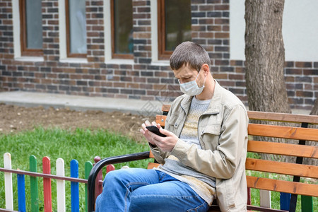 一个在街上蹲椅子的男人看着电话屏幕图片