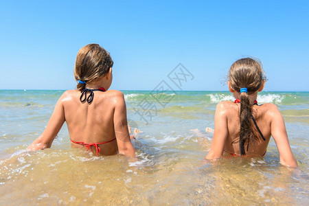 孩子们坐在岸边的水里看着距离图片