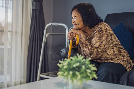 幸福的老年妇女家里客厅有木拐杖背景图片