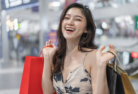在商场装购物袋的快乐年轻女子图片