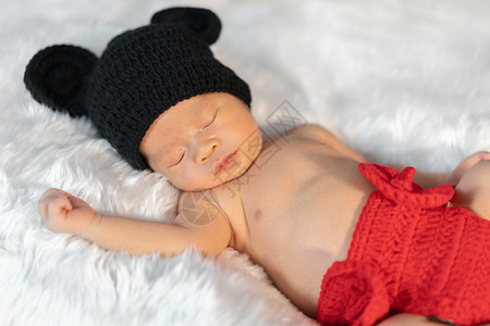 穿着老鼠服装的新生婴儿睡在毛皮床上图片