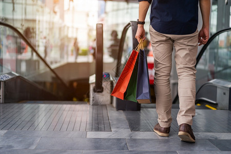 在商场散步时青年男子腿上靠近的一条背着购物袋图片