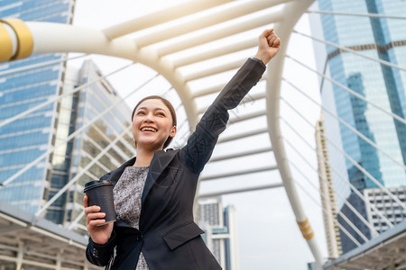 成功的商业妇女在城市中举起手来图片