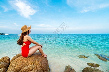 身穿泳装的年轻女子坐在泰国拉永高文诺克岛海滨石滩上图片