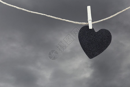 黑心纸挂在雨云背景的棕色黄绳上关于爱和心碎的观念背景图片