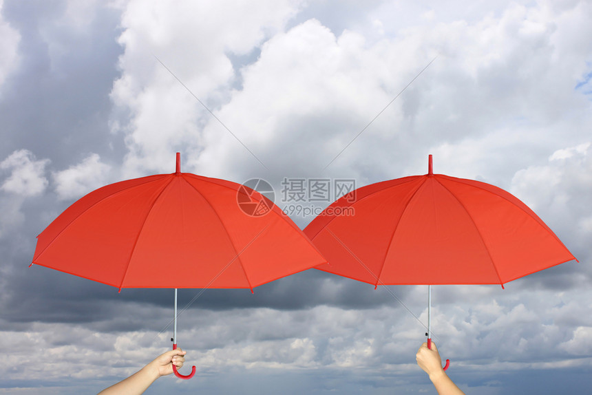 两个红伞手握着雨保护管理商业概念的关于雨云背景