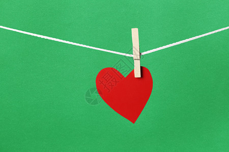 红纸心挂在绳子上情人节的概念和绿色背景图片