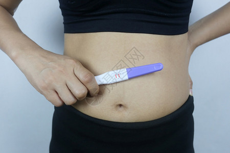 妇女手中的怀孕测试工具检结果显示怀孕身着黑衣的妇女图片
