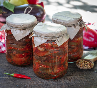 罐装茄子切片在木制桌上的玻璃罐中加辣味蔬菜酱图片