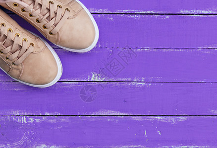粉红色的一对女皮鞋上面有紫色木本底的鞋带背景图片