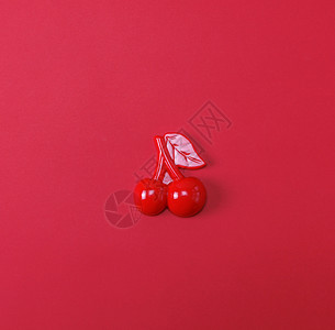 红色背景的塑料儿童玩具樱桃图片