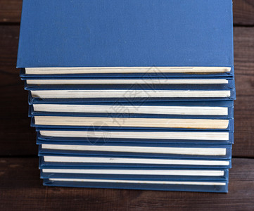 棕色木制桌子上蓝封面的大堆书图片