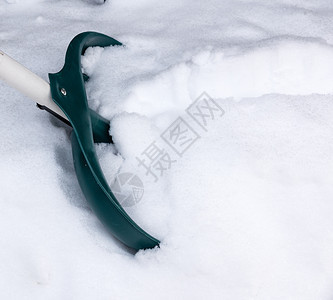 冬季一日积雪中露出塑料绿色铲子图片