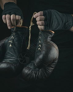 一对非常老式的拳击运动手套在男子中用黑色绷带套上图片