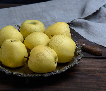 棕色木制桌子上成熟的新鲜黄苹果关闭图片