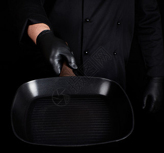 黑衣和乳胶大厨手套带有黑色背景的空方格烧烤锅图片