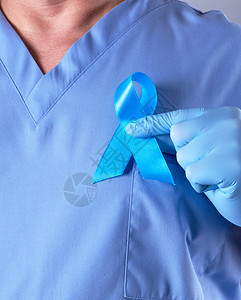 蓝制服医生和手握蓝丝带的乳胶手套蓝丝带是前列腺癌斗争和治疗的象征图片