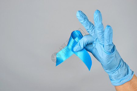 手握蓝丝带的色乳胶手套握蓝丝带是前列腺癌抗争和治疗的象征复制空间图片
