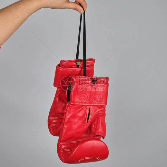 一对红色皮革拳击手套挂在一根灰色背景的绳子上图片