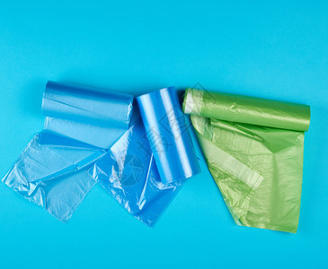 三卷装满塑料垃圾袋的卷子蓝色背景背景图片