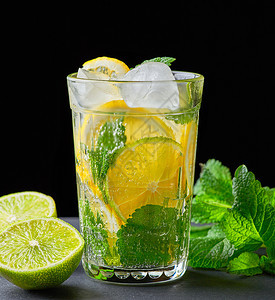 用柠檬和绿色薄荷叶制成的冷水在杯中加滴紧靠柠檬的配料图片