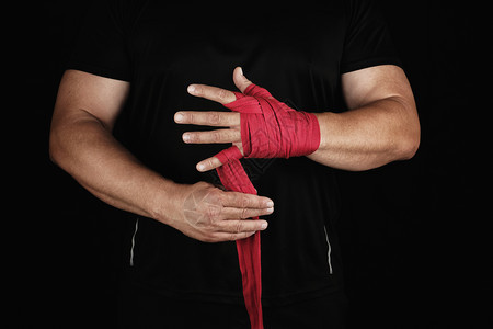 运动员身着黑色衣服在训练前用红色纺织弹绷带包着双手黑背景在训练前用红色纺织弹绷带包起来图片