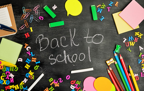 学校用品多色木铅笔记本纸贴剪铅笔磨机和以黑色背景返回学校的白粉笔童背景图片