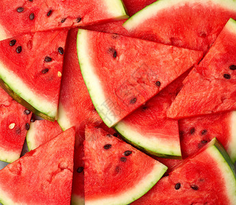 三角切片成熟的红西瓜棕籽明亮的夏季纹理背景图片
