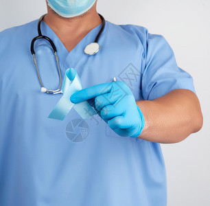 身穿制服和乳胶手套的医生握蓝丝带象征前列腺癌的抗争和治疗图片