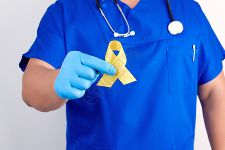 身穿蓝制服的医生和无菌乳胶手套,上握着黄丝带,象征与猫肿瘤的斗争,问题及其预防,近距离结束。图片