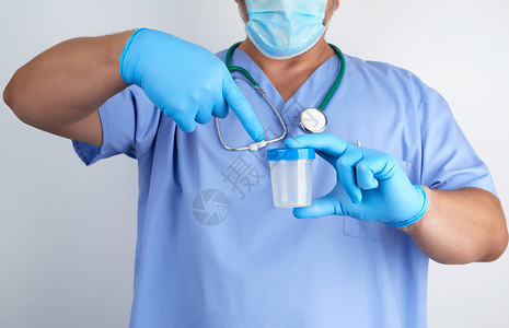 穿蓝色制服和乳胶手套的医生拿着一个空塑料容器用于取尿液样本并关闭图片