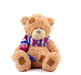 棕褐色可爱泰迪熊有彩色织围巾的补丁坐在孤立的白色背景上关背景图片