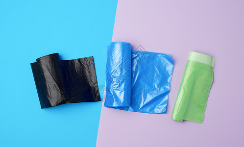 三卷装满塑料垃圾袋的卷子蓝色背景背景图片