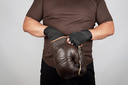 男人站在手上戴着古老的棕色拳击手套白背景图片