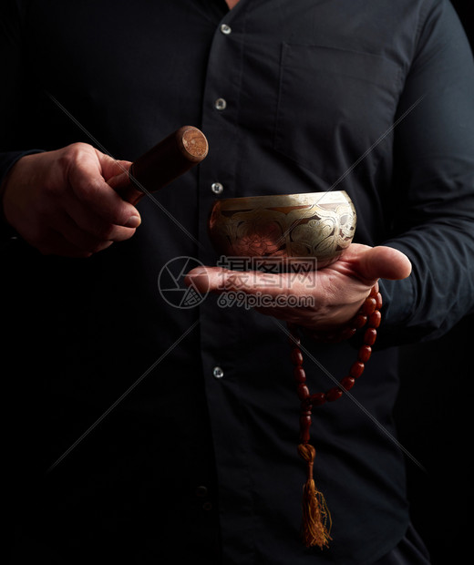 穿黑衬衫的人拿着藏黄铜歌碗和木棍这是冥想祈祷和沉浸在昏睡中的仪式图片
