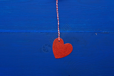 纸红色闪亮的装饰心形挂在一根绳子上背景为深蓝色木质抽象的节日背景为2月14日的情人节装饰元素图片