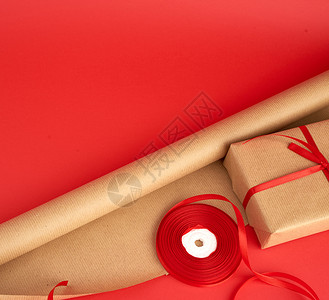 包装用棕色纸红丝带卷和背景上棕色Kraft纸包装礼物图片