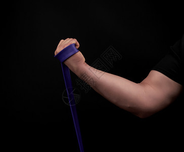 身穿黑衣肌肉的运动员正在用低密钥紫色橡胶运动进行锻炼图片