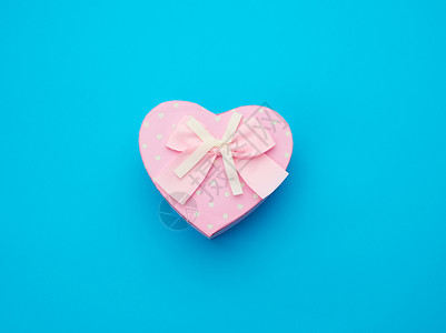 粉红礼物盒以心脏的形式蓝底顶视图喜庆背景的弓形心图片